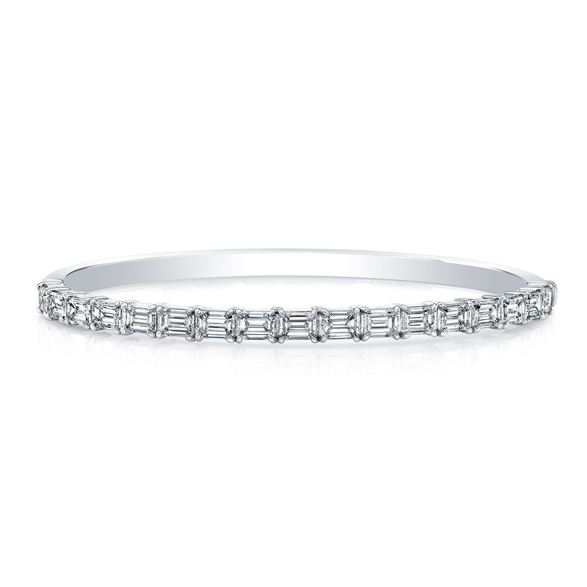 An emerald cut diamond bangle bracelet crafted in white gold, with diamonds set half way around the bracelet.