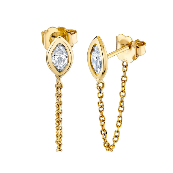 A pair of Norman Silverman 18k gold earrings with marquise-shaped diamonds encased in bezel settings, hanging from chains.