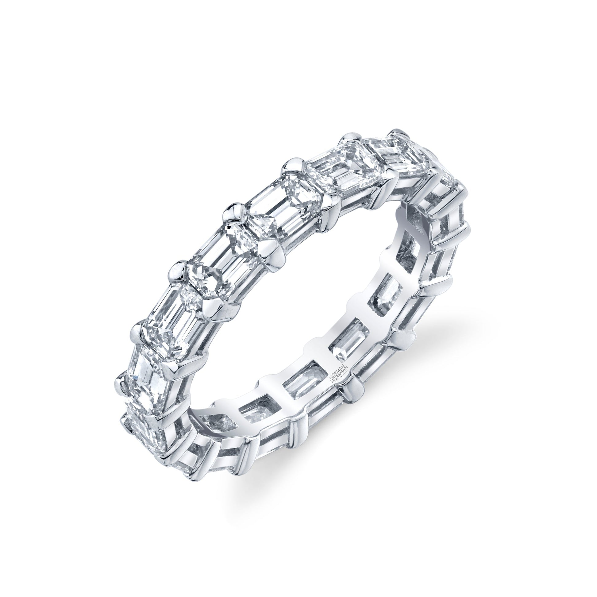 An 18k white gold Norman Silverman eternity band featuring a series of emerald cut diamonds set around its circumference.