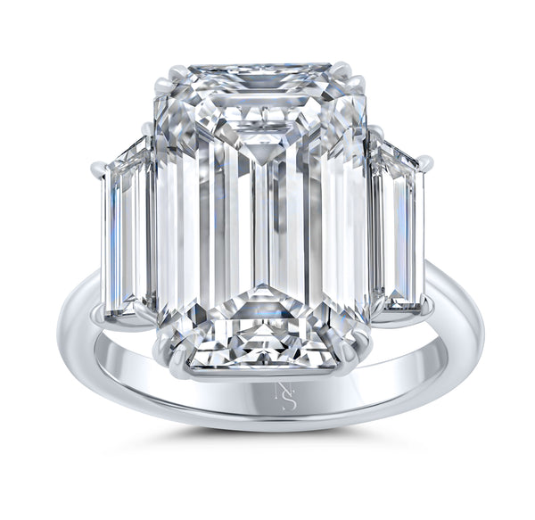 An emerald cut diamond ring with two side stones on a platinum band.
