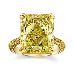 A 13.08 carat fancy yellow radiant diamond ring with a pave band set in 18k yellow gold.