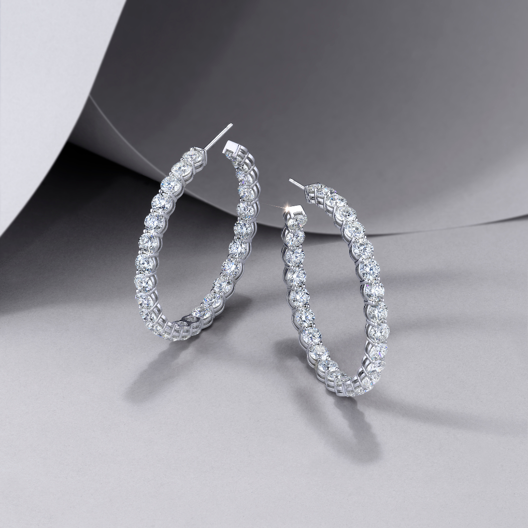 Pair of white  gold hoop earrings with on a gray background