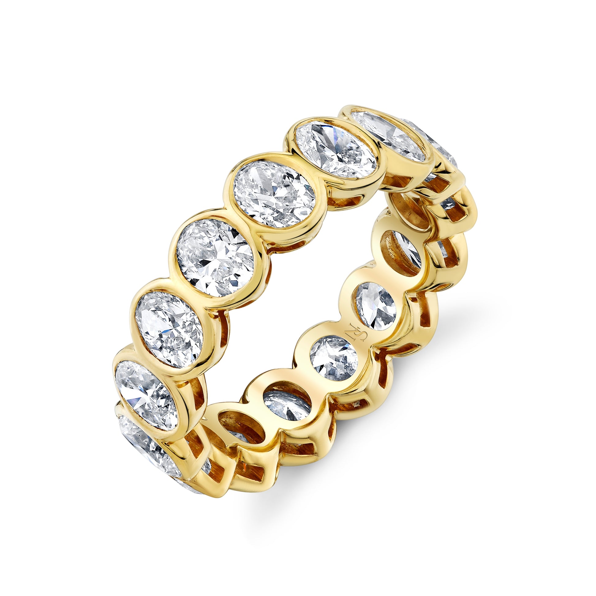 A gold eternity band ring with bezel set oval diamonds