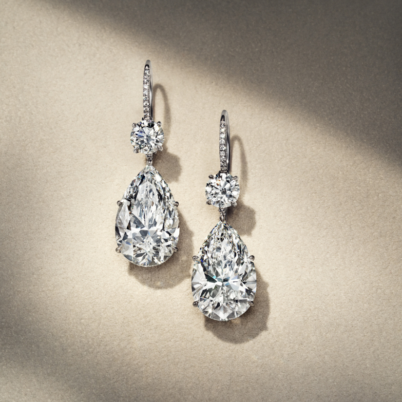 Pair of diamond earrings on a beige background