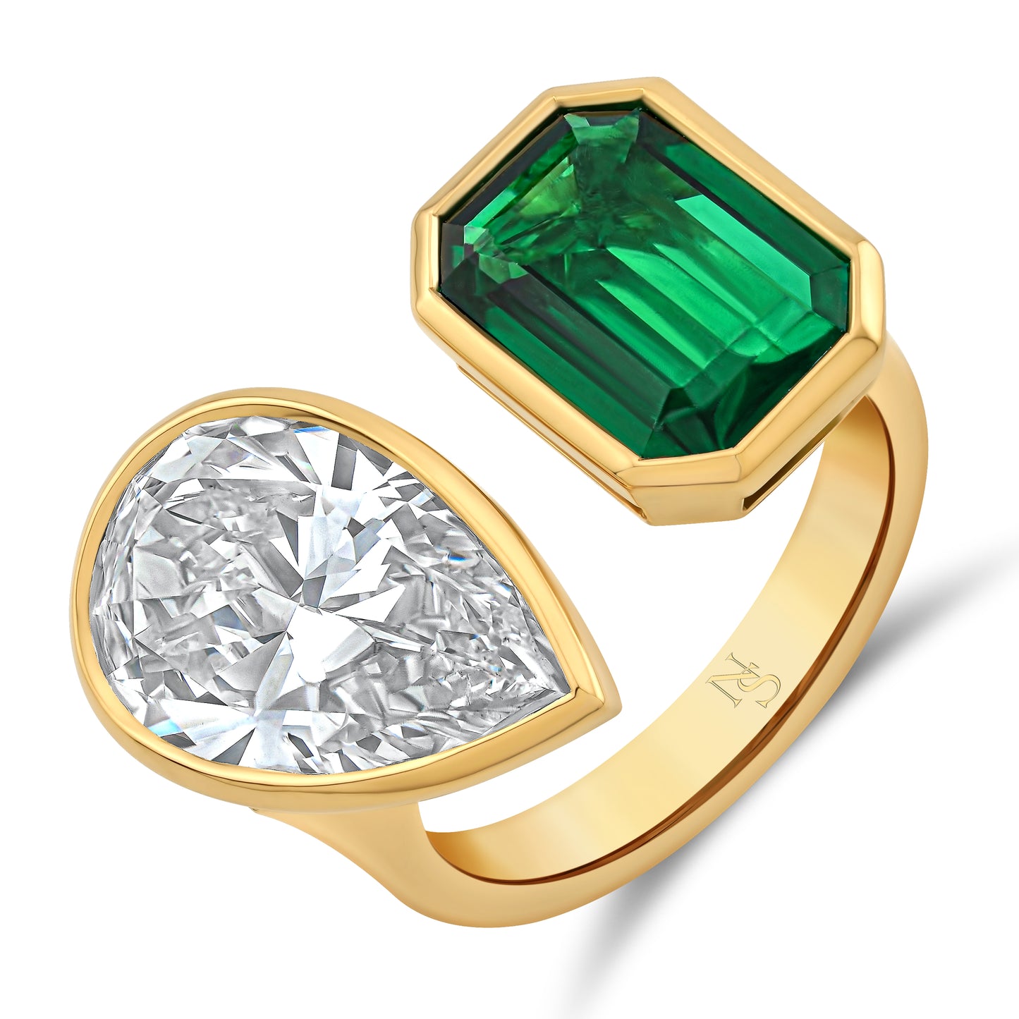 A twin ring with one pear-shaped diamond and one rectangular green emerald, set in 18k yellow gold.
