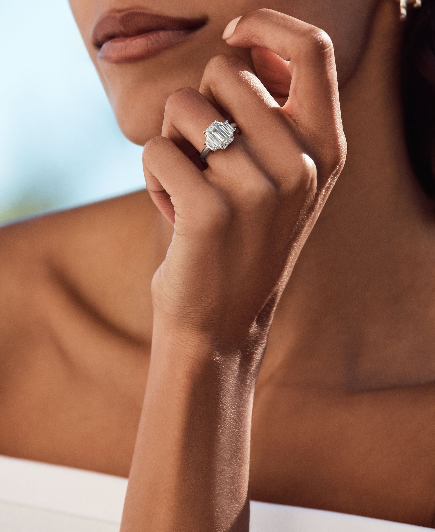 Close-up of a hand wearing a diamond ring with trapezoid-shaped side diamonds.